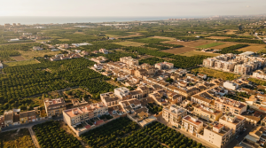 Vista aérea de pueblo del área metropolitana de Valencia con huerta y skyline al fondo